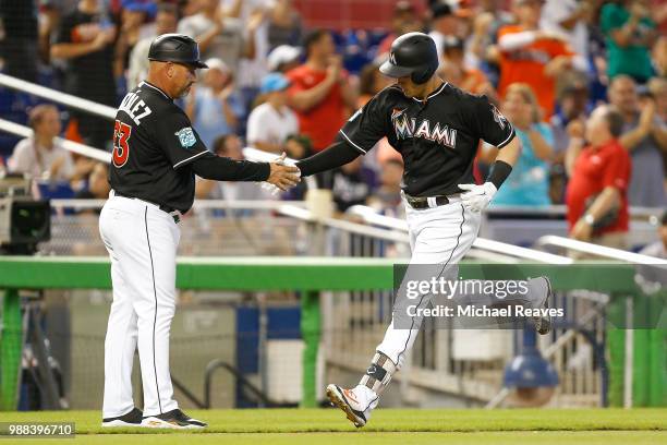Brian Anderson of the Miami Marlins high fives third base coach Fredi Gonzalez of the Miami Marlins after hitting a two-run home run in the sixth...