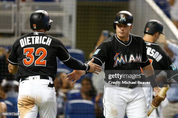 Derek Dietrich of the Miami Marlins high fives Justin Bour after scoring in the sixth inning against the New York Mets at Marlins Park on June 30,...