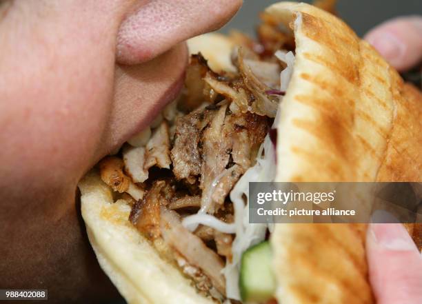 Woman eats a doner kebab at a kebab restaurant in Hanover, Germany, 27 November 2017. Photo: Peter Steffen/dpa