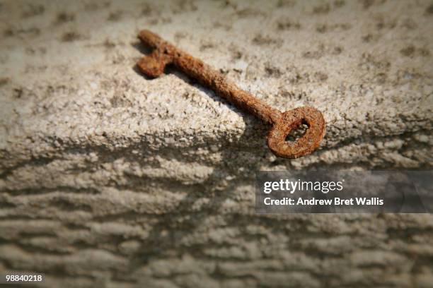 old rusty key on a stone ledge - key stone stock pictures, royalty-free photos & images