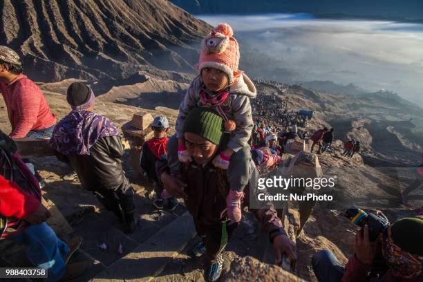 Tenggerese carrying his child while climbing Mount Bromo during the ceremony of Yadnya Kasada Festival at Probolinggo, East Java, on 30th April 2018....