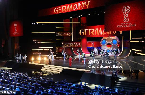 Singer Larisa Dolina from Russia sings onstage while the word "Germany" is displayed on video screens during the FIFA 2018 World Cup draw, at the...