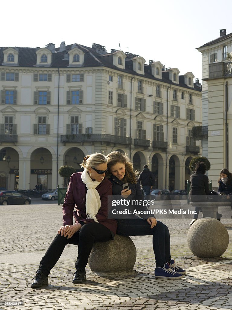 Mother and daughter check text message, in piazza