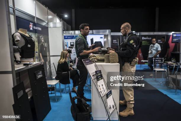 An exhibitor shows an attendee armor from a bullet-proof vest during the Rio International Defense Exhibition in Rio de Janeiro, Brazil, on Friday,...