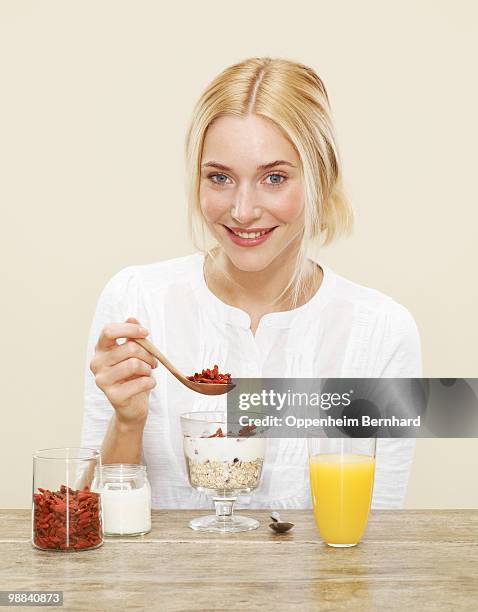 female sprinkling goji berries over her breakfast - goji berry stock pictures, royalty-free photos & images