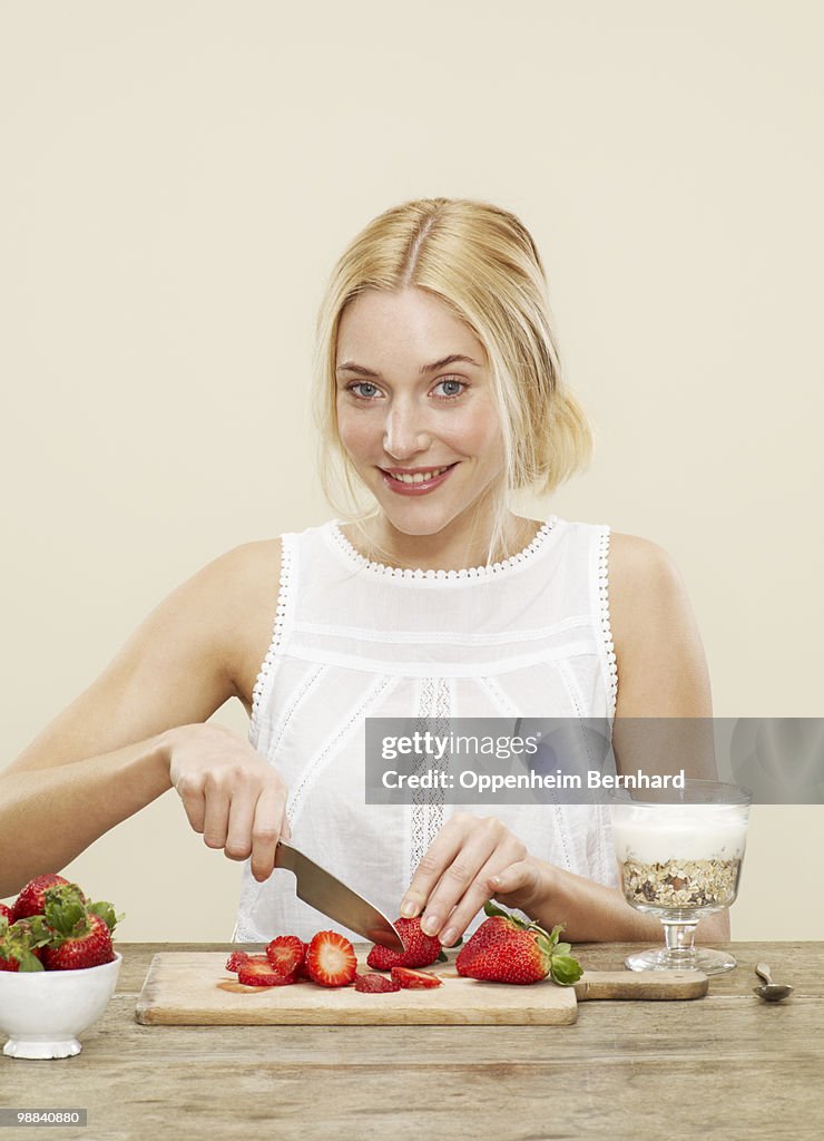 Female cutting up strawberries for her breakfast