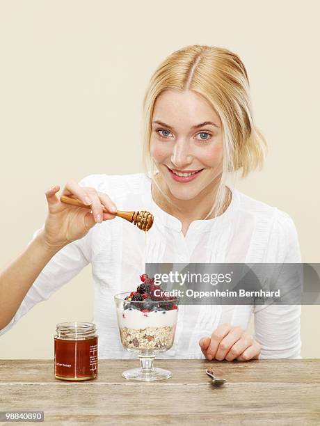 female drizzling honey over healthy breakfast - bearberry stock pictures, royalty-free photos & images