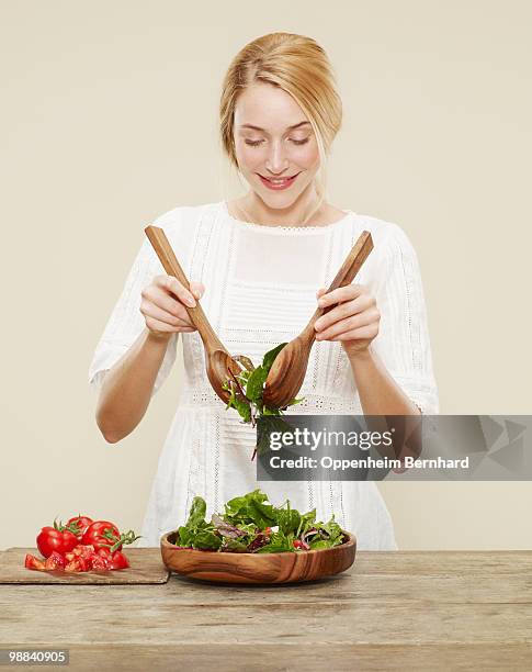 female smiling as she tosses a fresh salad - salad imagens e fotografias de stock