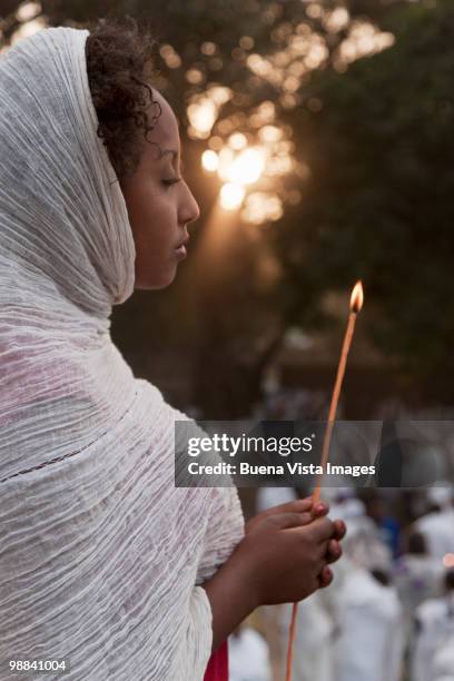 woman with candle praying at timkat - dupatta foto e immagini stock