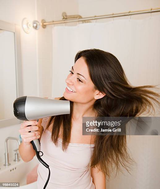 woman blowdrying hair in bathroom - hair dryer fotografías e imágenes de stock