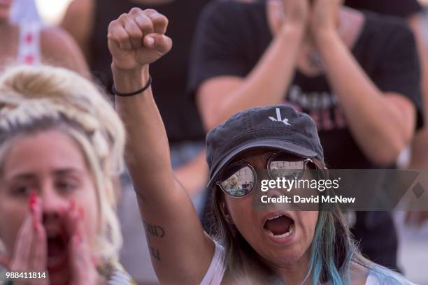 The Metropolitan Detention Center is reflected in the glasses of a woman attending a protest outside the center on June 30, 2018 in Los Angeles,...