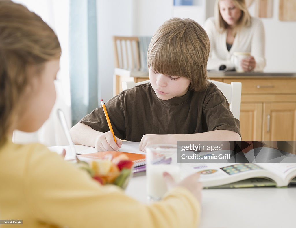 Brother and sister doing homework at kitchen table