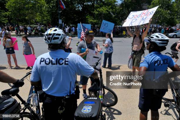 Protestors counter Howard Caplan, a local Trump supporter who holds a sign that reads God Bless Trump, as he stands, surrounded by Police officers,...