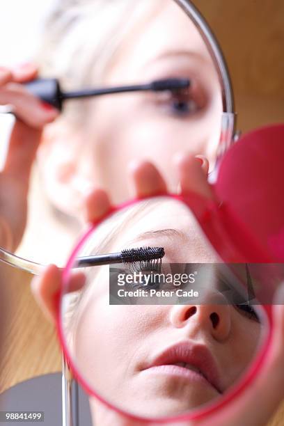girl putting mascara on in mirror - cade stockfoto's en -beelden