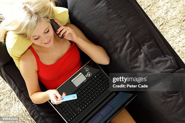 girl on sofa with laptop using credit card - cade stockfoto's en -beelden