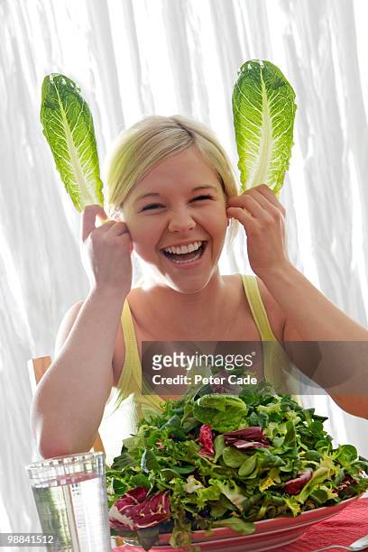 girl with large bowl of lettuce,making rabbit ears - cade stock-fotos und bilder