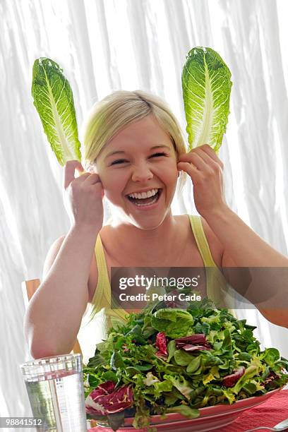 girl with large bowl of lettuce,making rabbit ears - funny vegetable stockfoto's en -beelden