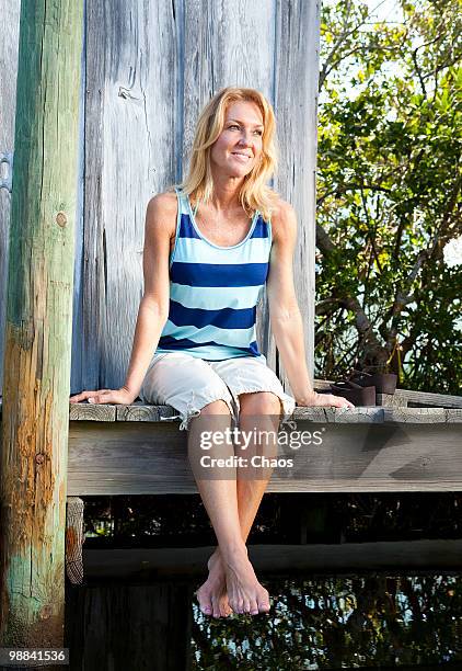 woman sitting dangling her legs off a dock - newoutdoors stock pictures, royalty-free photos & images