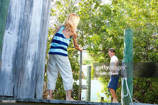 woman spraying a man with water on a dock - newoutdoors stock pictures, royalty-free photos & images