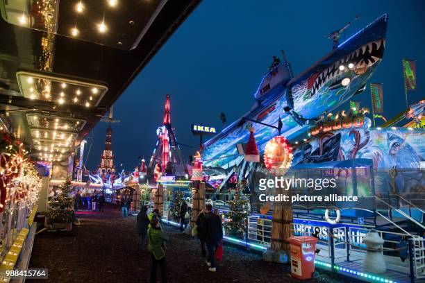 Visitors stroll past festive decorated Christmas stalls at the newly opened Christmas market on the Landsberger Allee road in Berlin, Germany, 1...