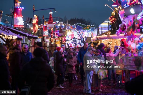 Visitors stroll past festive decorated Christmas stalls at the newly opened Christmas market on the Landsberger Allee road in Berlin, Germany, 1...