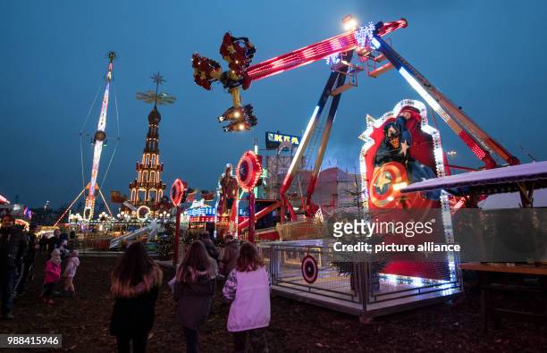 Visitors stroll past festive decorated Christmas stalls and fairground rides at the newly opened Christmas market on the Landsberger Allee road in...