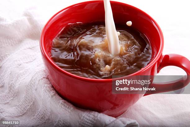 milk splashes into coffee mug - shana novak stock pictures, royalty-free photos & images