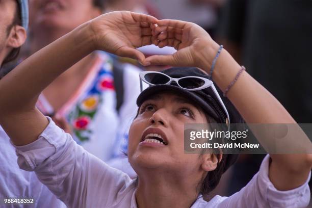 Woman makes a heart gesture toward detainees held inside the Metropolitan Detention Center, after marching to decry Trump administration immigration...