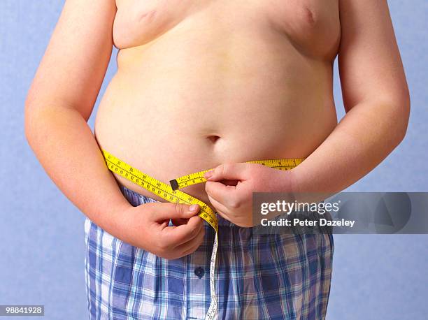 overweight 12 year old boy measuring himself - barrigón fotografías e imágenes de stock