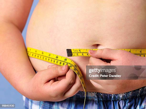 obese 12 year old boy measuring himself - obesitas stockfoto's en -beelden