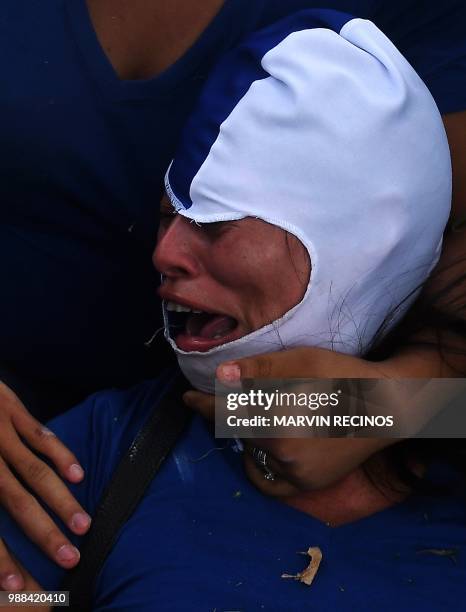 Anti-government protesters help an injured partner during clashes within the "Marcha de las Flores" in Managua, on June 30, 2018. - At least six...