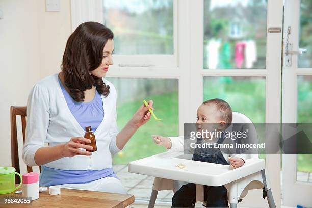 mum giving baby syrup in kitchen - esslöffel stock-fotos und bilder