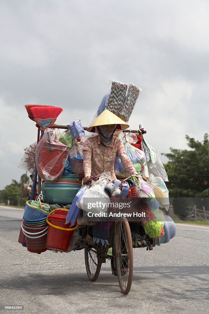 Woman riding overloaded bicycle, Hanoi, Vietnam