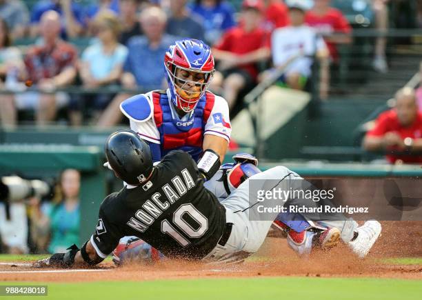Robinson Chirinos of the Texas Rangers tags out Yoan Moncada of the Chicago White Sox at home in the first inning of a baseball game at Globe Life...