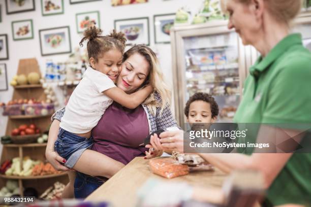 Single mother with her mixed-race kids is making a contactless payment at the store