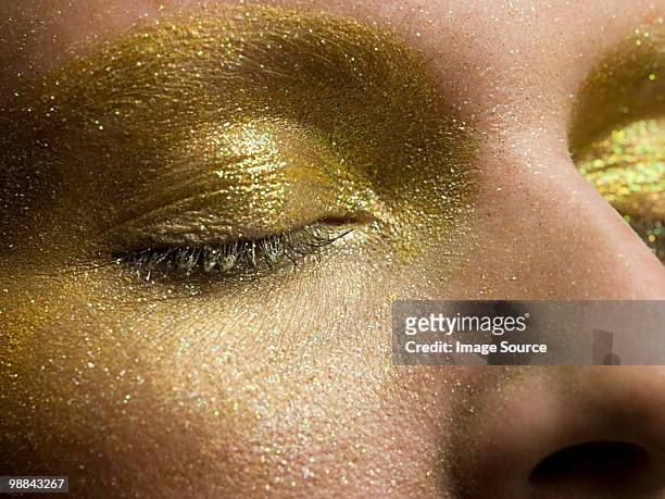 female eyes covered in gold make up - shiny skin stock pictures, royalty-free photos & images