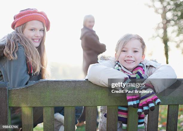 sisters sitzen auf bank im freien im herbst - geschwister altersunterschied stock-fotos und bilder