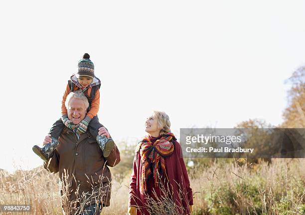 großeltern mit enkel zu fuß im freien - family walking stock-fotos und bilder