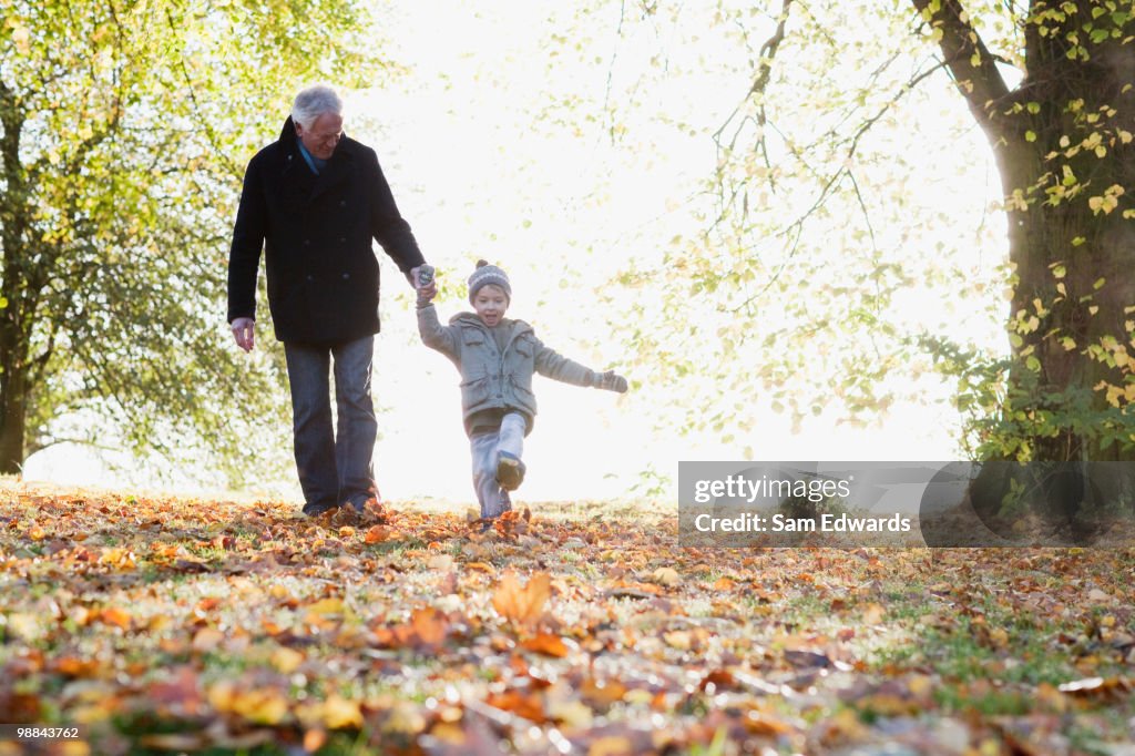 Grandfather walking outdoors with grandson in autumn