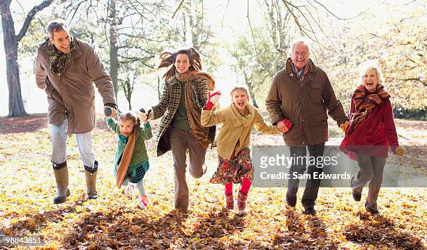 extended family running in park in autumn - sam day stockfoto's en -beelden