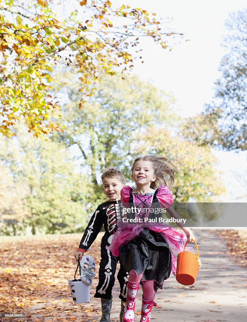Children in Halloween costumes running in park