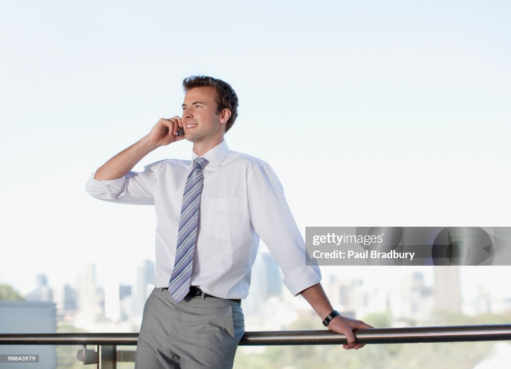 Businessman talking on cell phone on balcony