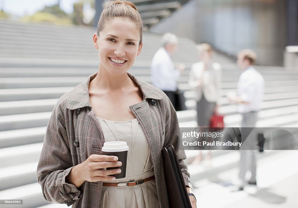 Businesswoman holding coffee outdoors