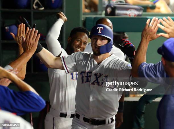 Ryan Rua of the Texas Rangers gets high fives in the dugout after a solo home run in the fifth inning against the Chicago White Sox in a baseball...