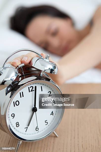 woman reaching out for alarm clock - alarm clock on nightstand stock pictures, royalty-free photos & images