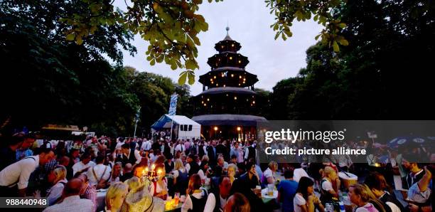 July 2014, Germany, Munich: Countless visitors of the traditional Kocherlball sitting by the beer tables at the Chinese Tower in the English garden....