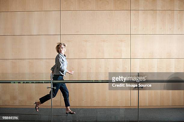 businesswoman running through corridor - running indoors stock pictures, royalty-free photos & images