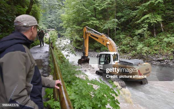 June 2018, Germany, Garmisch-Partenkirchen: Roland Achnter, the manager responsible for the gorge of Garmisch-Partenkirchen, watches a bulldoyer...