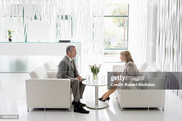 business people having meeting in office lobby - side profile face to face stock-fotos und bilder