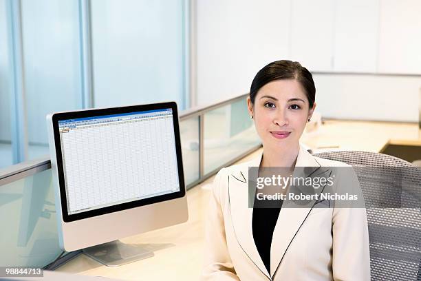 businesswoman sitting at desk in office - robert moreno fotografías e imágenes de stock